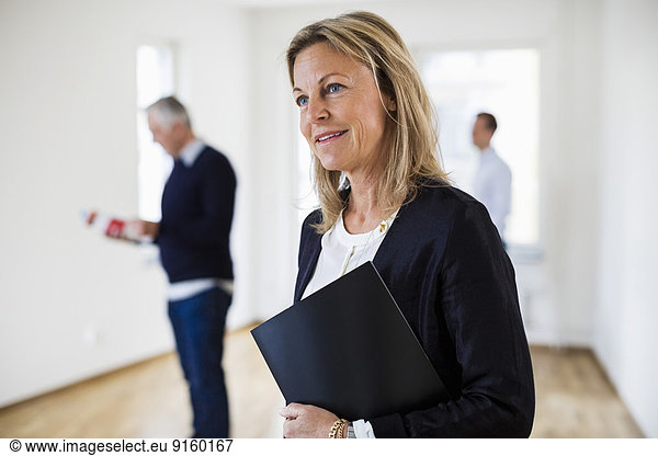 Thoughtful real estate agent with colleague and man in background at home