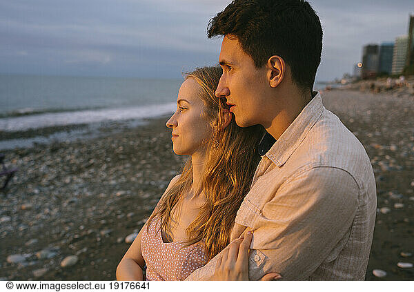 Thoughtful romantic couple embracing at beach
