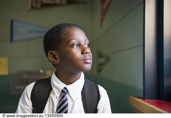 Thoughtful schoolboy standing by window