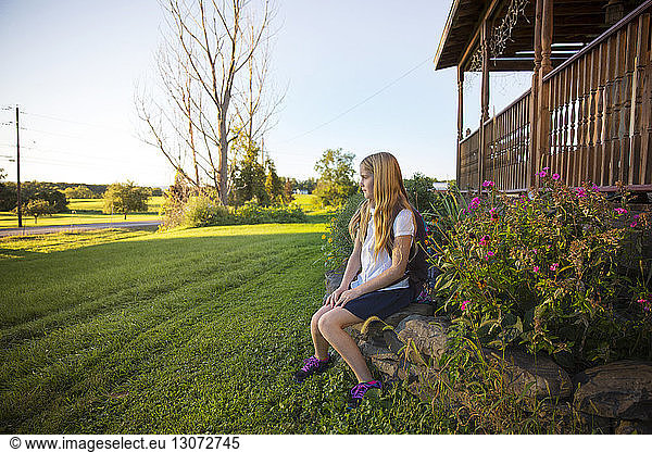 Thoughtful schoolgirl sitting on stones at yard