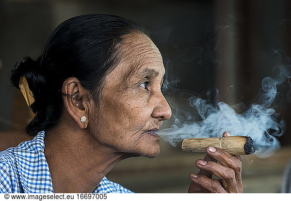 Thoughtful senior Burmese woman smoking cigar  Bagan  Myanmar