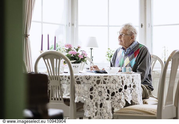 Thoughtful senior man sitting on dining table at nursing home
