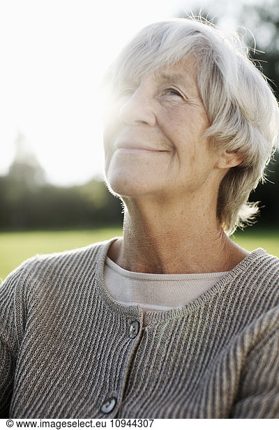 Thoughtful senior woman looking up in back yard