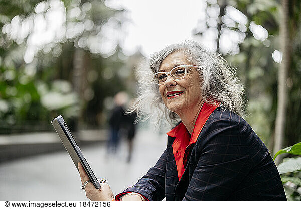 Thoughtful smiling businesswoman with tablet PC