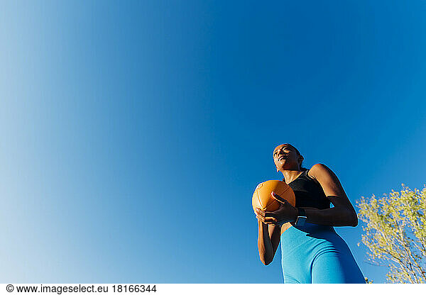 Thoughtful sportswoman with American football on sunny day