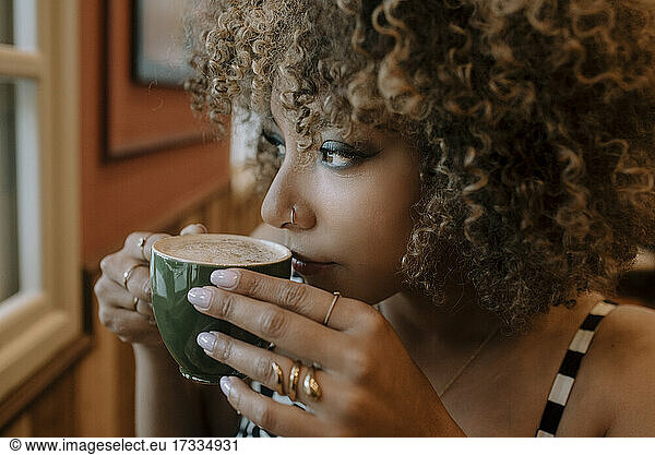 Thoughtful woman drinking coffee at cafe