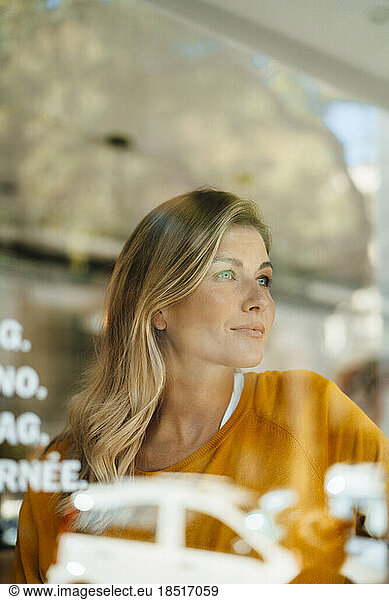 Thoughtful woman in cafe seen through glass