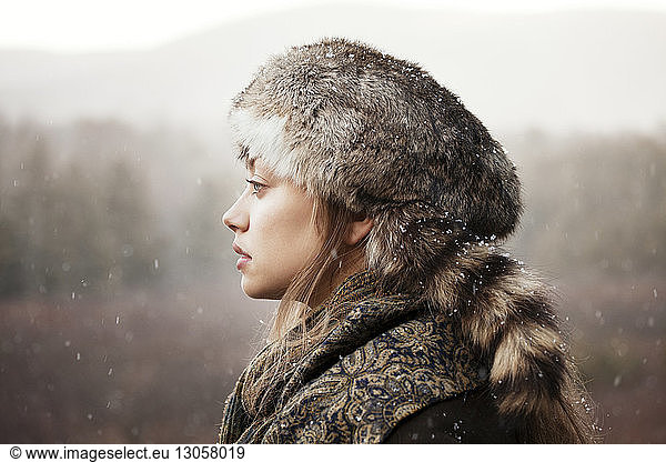 Thoughtful woman in warm clothing near forest