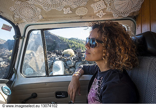 Thoughtful woman looking away while wearing sunglasses in camper trailer