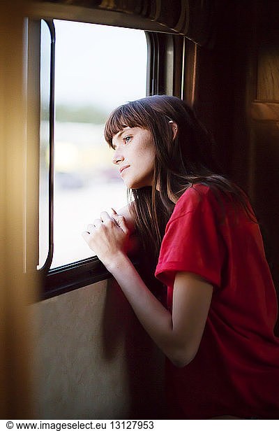 Thoughtful woman looking outside window while travelling in camper van