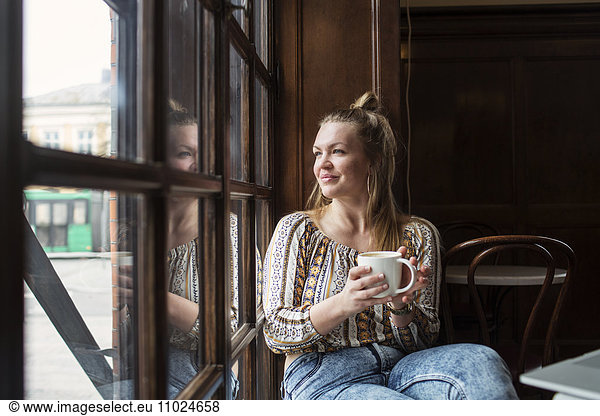 Thoughtful woman looking through window while sitting at cafe