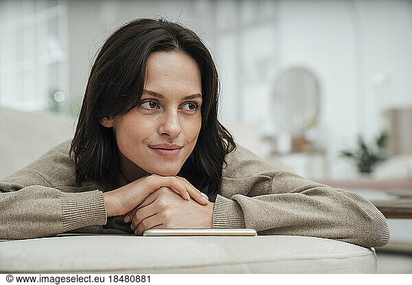 Thoughtful woman lying on sofa at home