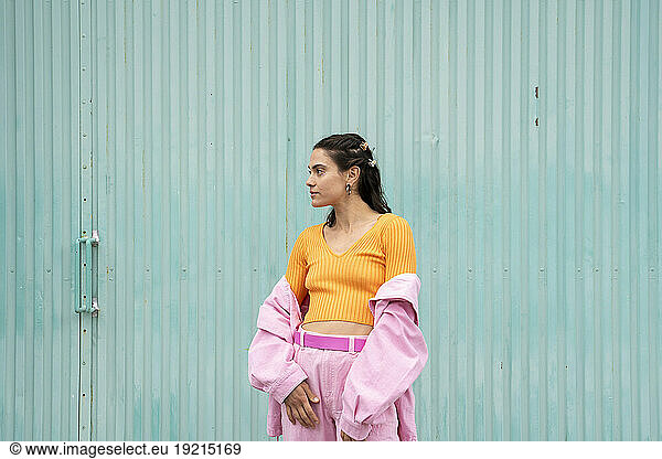 Thoughtful woman standing in front of blue shutter door