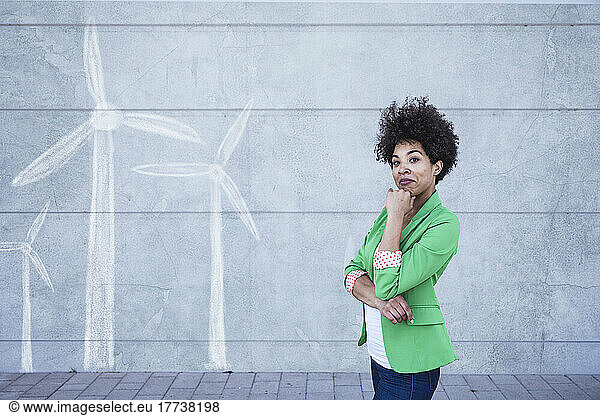 Thoughtful woman standing in front of wall with painted wind turbines