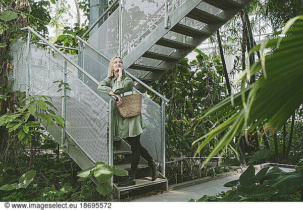 Thoughtful woman standing on staircase in greenhouse