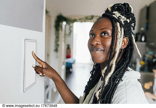 Thoughtful woman using home automation on wall at home