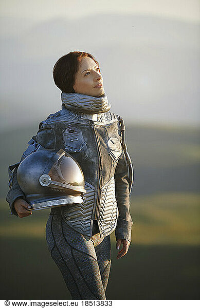 Thoughtful woman wearing astronaut costume holding space helmet