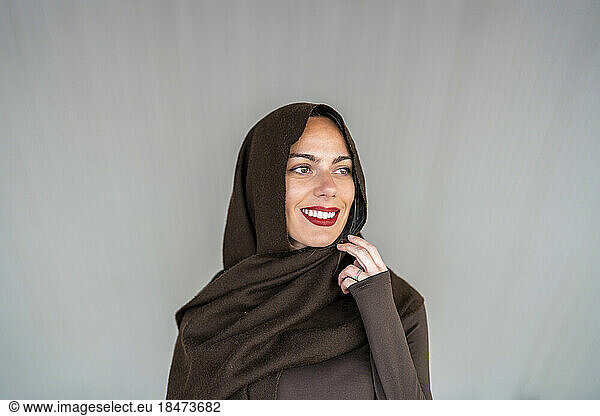Thoughtful woman wearing hijab against gray background