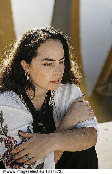 Thoughtful woman with arms crossed sitting in evening