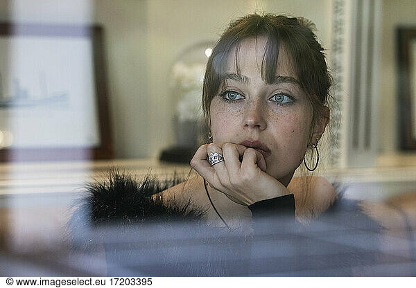 Thoughtful woman with bangs sitting at cafe looking away