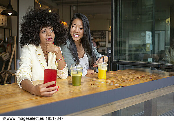 Thoughtful woman with hand on chin sitting with friend in cafe