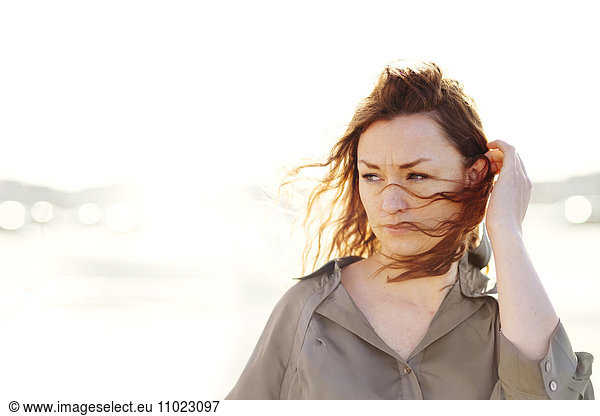 Thoughtful woman with windswept hair outdoors