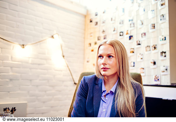 Thoughtful young businesswoman looking away in creative office