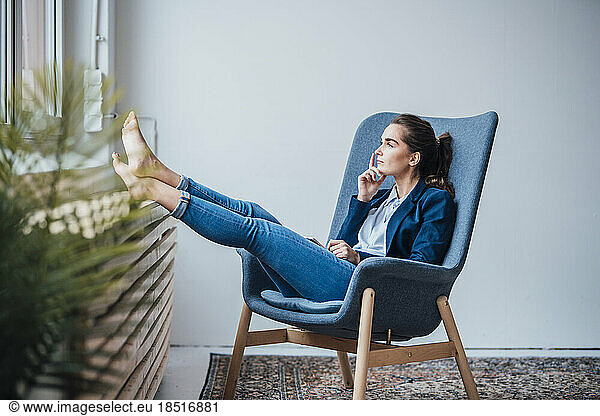Thoughtful young businesswoman sitting on armchair