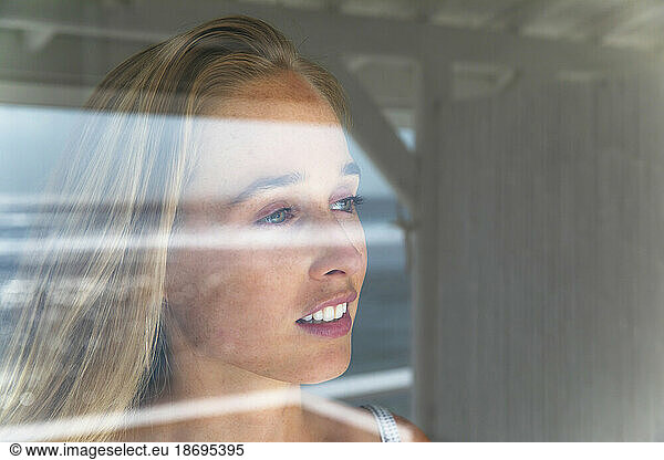 Thoughtful young woman looking through window