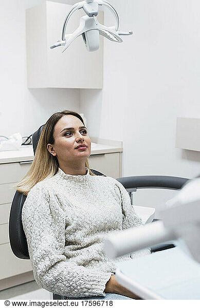 Thoughtful young woman sitting on dentist chair at clinic