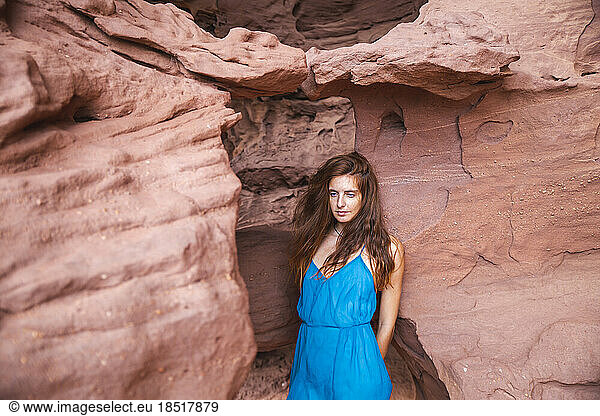 Thoughtful young woman standing in front of red rock