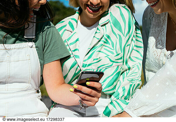 Three anonymous female friends using mobile phone and having fun