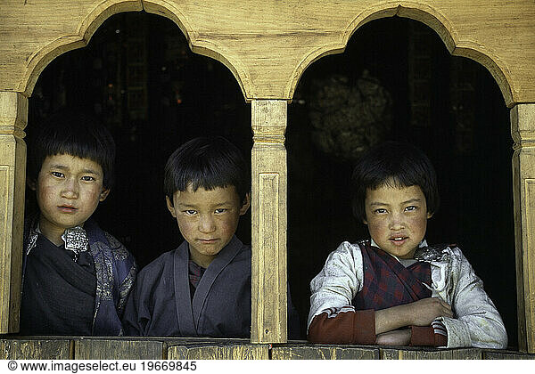 Three boys look out a window in Paro  Bhutan.