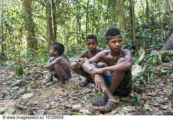 Three boys of the Orang Asil tribe sitting on the ground in the jungle  native  indigenous Volk  tropical rain forest  Taman Negara National Park  Malaysia  Asia