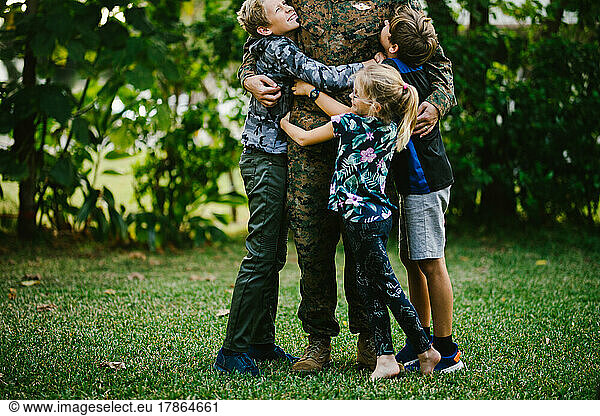 Three children hug service member father after deployment