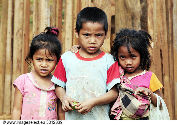 Three children looking critically towards the camera  Laos  Southeast Asia  Asia
