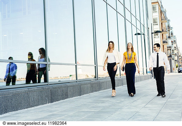 Three colleagues walking in city street