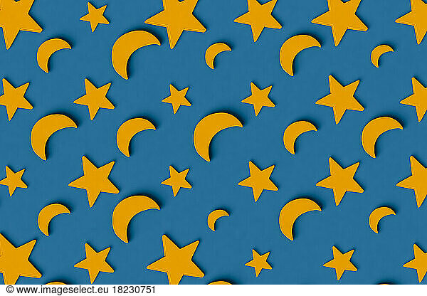 Three dimensional pattern of rows of yellow stars and crescent moons flat laid against blue background