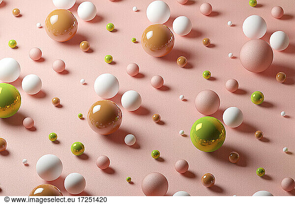 Three dimensional pattern of various spheres flat laid against pink background