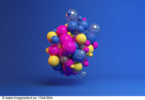 Three dimensional render of colorful spheres floating against blue background