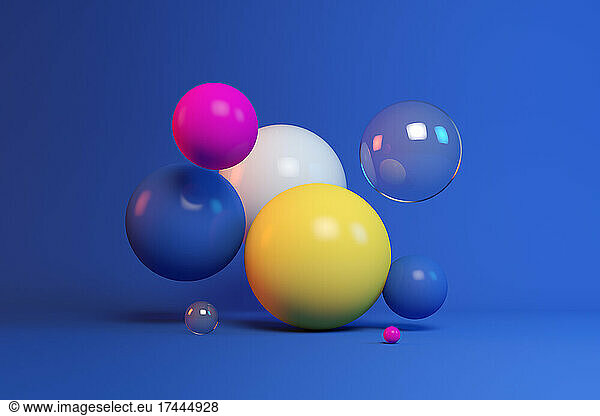 Three dimensional render of colorful spheres floating against blue background
