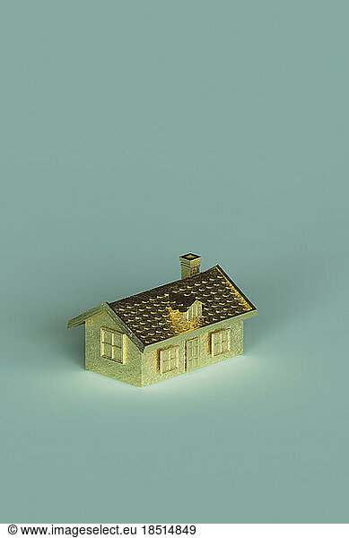 Three dimensional render of gold colored house standing against turquoise background