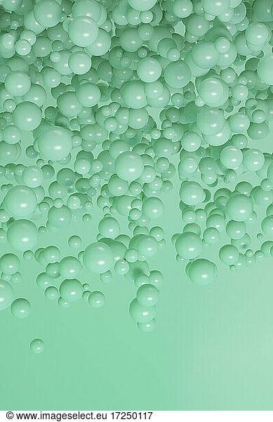 Three dimensional render of green spheres floating against green background