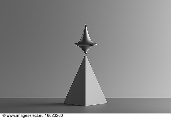 Three dimensional render of metallic top spinning on top of geometric pyramid