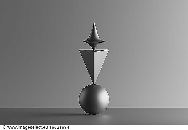 Three dimensional render of metallic top spinning on top of geometric pyramid and sphere