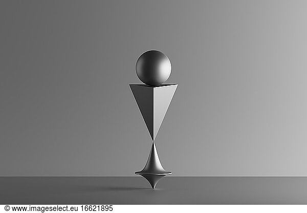 Three dimensional render of metallic top spinning under geometric pyramid and sphere
