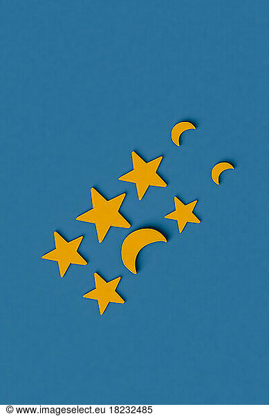 Three dimensional render of rows of yellow stars and crescent moons flat laid against blue background