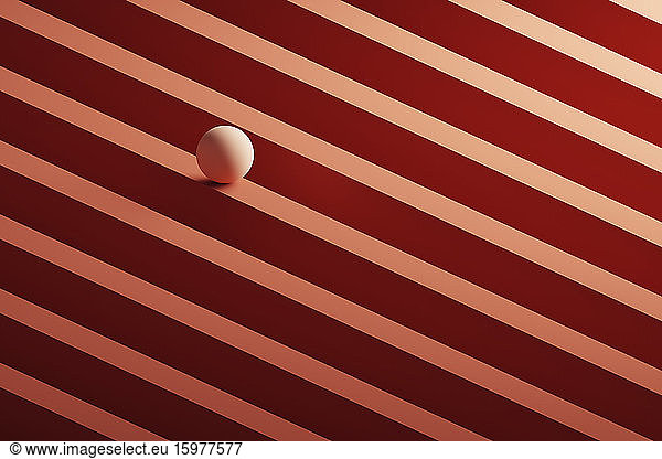Three dimensional render of small light brown sphere rolling over geometric pattern