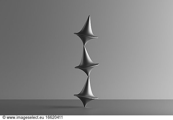Three dimensional render of three metallic spinning tops balancing on top of each other