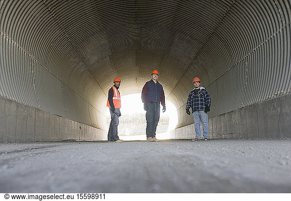 Three engineers standing in a tunnel at an asphalt plant